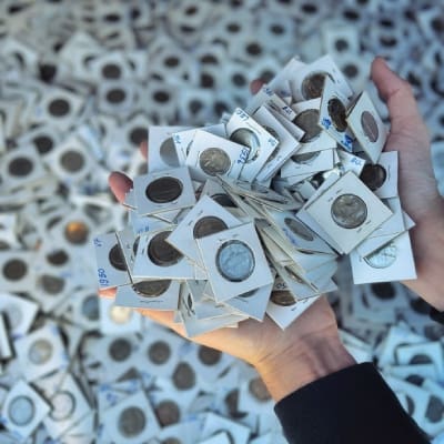 A pile of coins in holders held by a hand, highlighting the natural state of coins and the selling considerations.